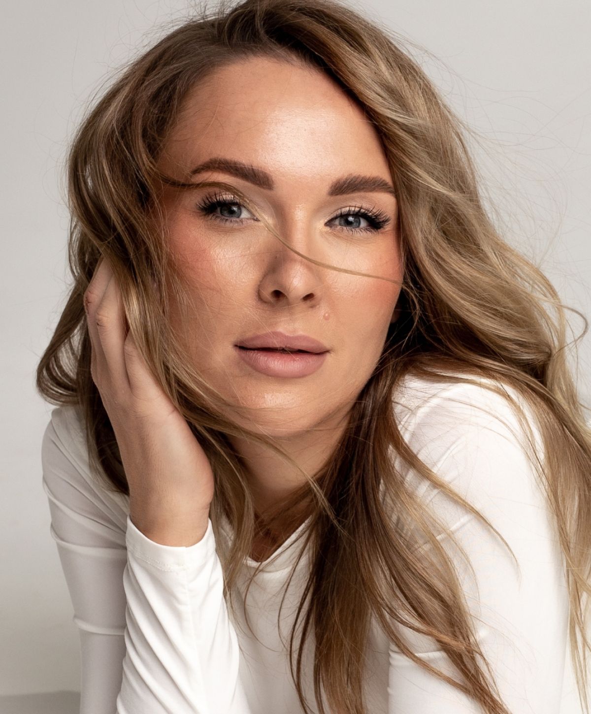 Woman with long hair, natural makeup, gentle pose.