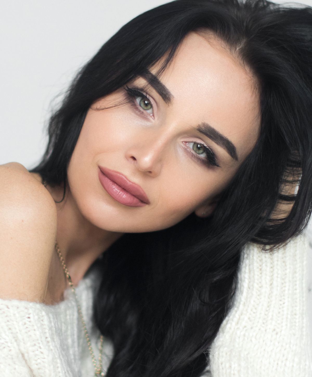 Woman with dark hair and green eyes, smiling.