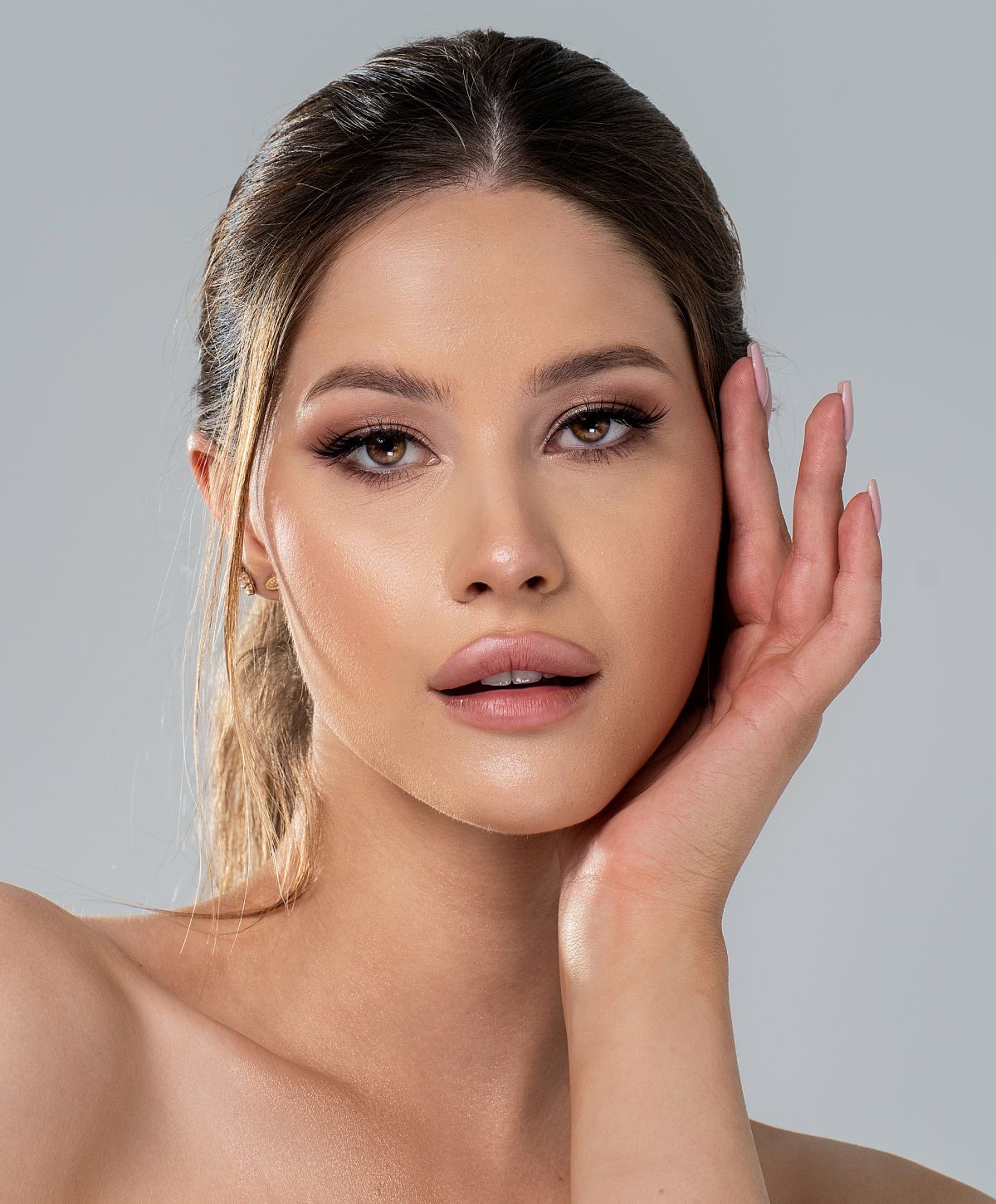 Model posing with hand on face, soft lighting.