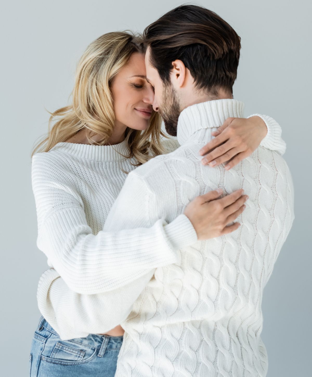 Couple embracing in cozy sweaters, smiling affectionately.
