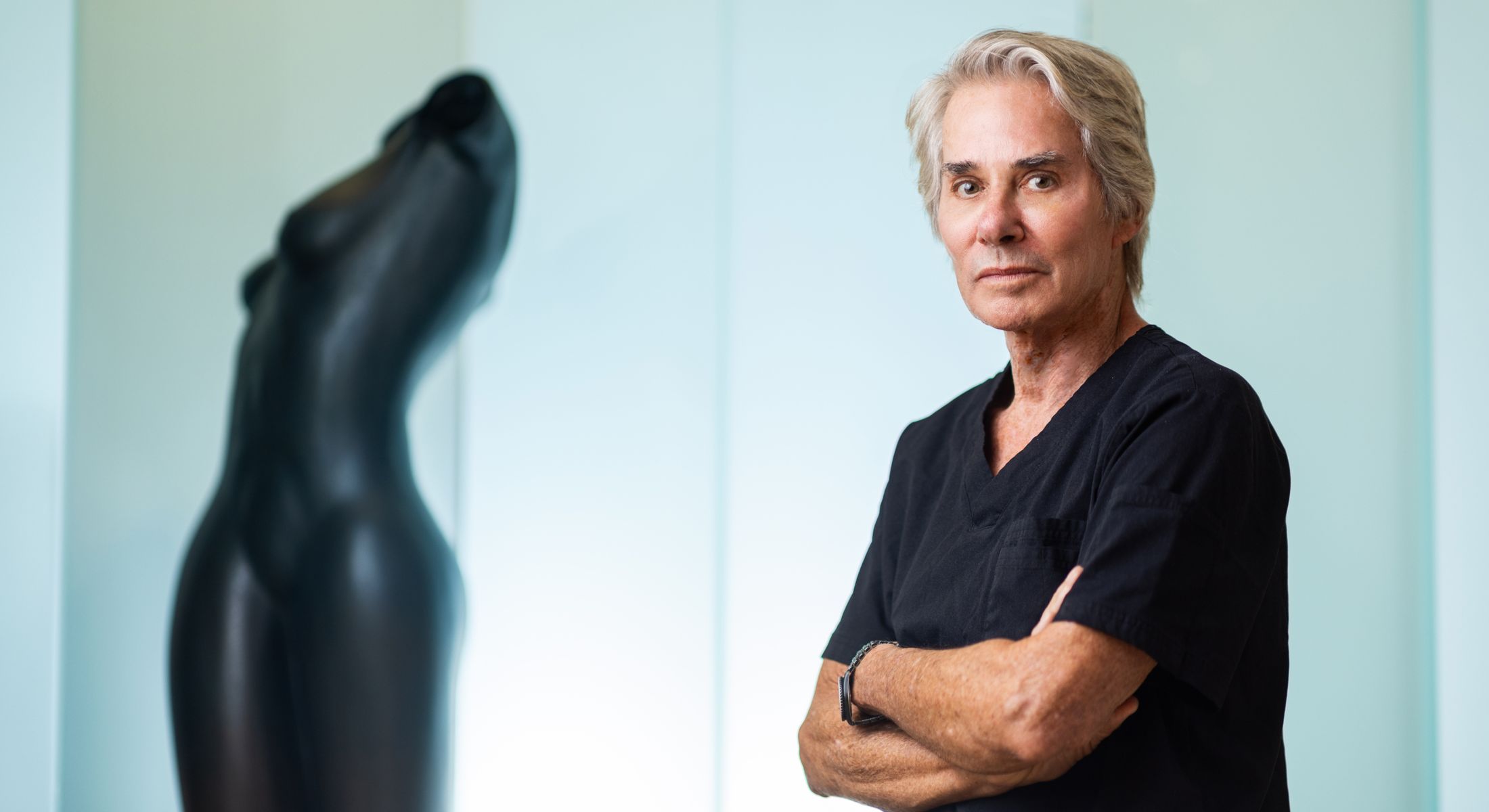 Man in black scrubs with artistic sculpture background.